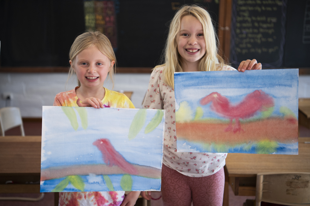 Mansfield Steiner Primary students holding images of their paintings of Waan the crow