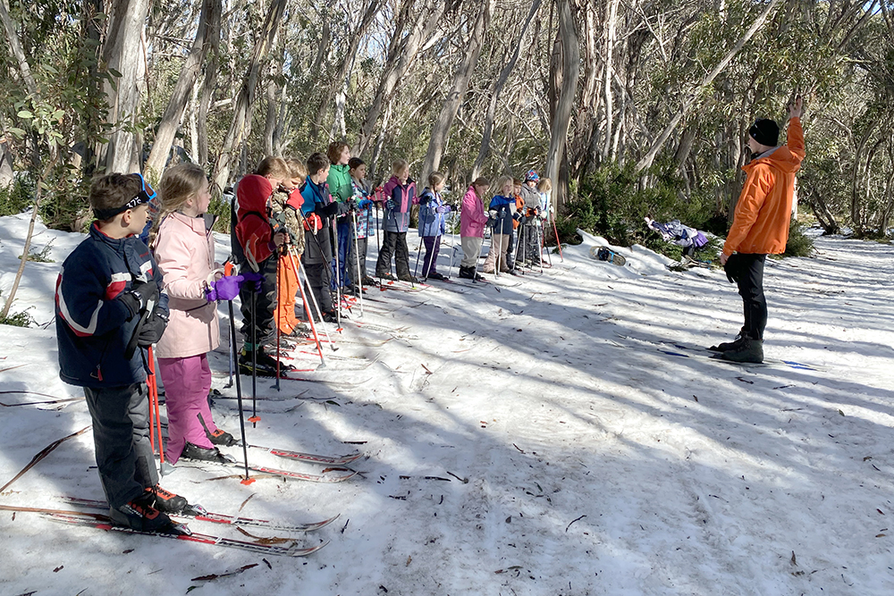 Class 2 students lined up on cross country skis in the snow, listening to an instructor at Mt Stirling.