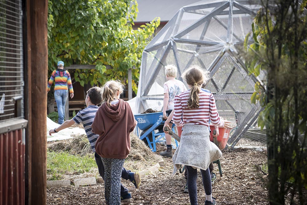 Students running through the vegetable garden with a hexagonal dome in the background