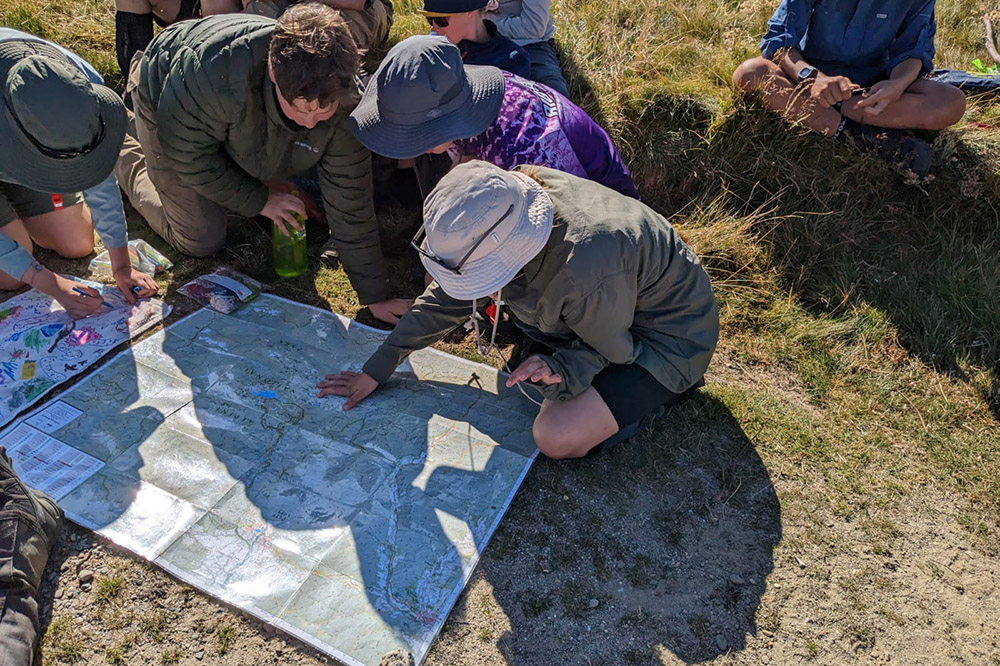 Student reading a large map on the ground planning the days walk